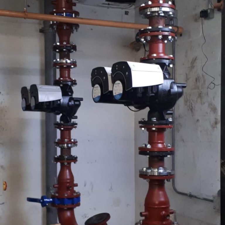 We can offer welding off site pipe sections Two pumps mounted on red pipes with valves in an industrial setting.