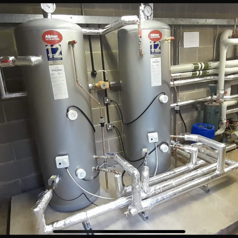 New DHW installation Two unvented water DHW vessels with piping and valves in a mechanical room.